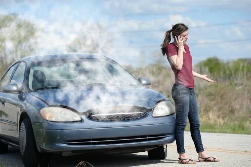 A teenage girl is broken down on the side of the road after car began to overheat